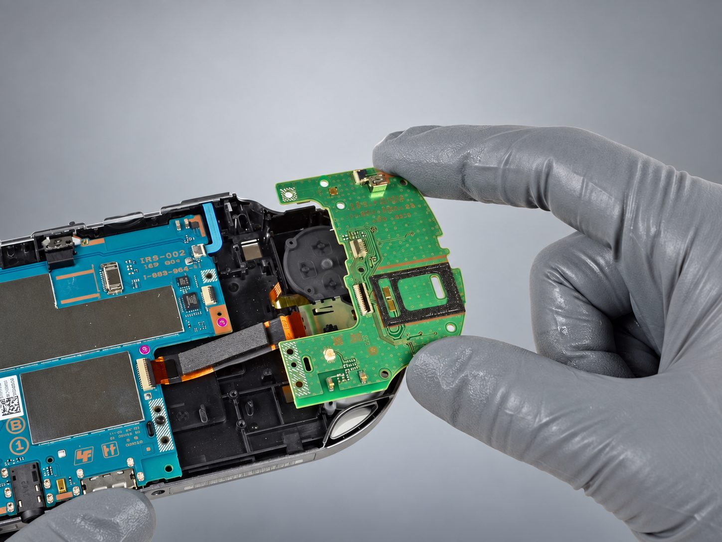 Tecnico con guanti sostituisce una scheda laterale della PS Vita Serie 1000